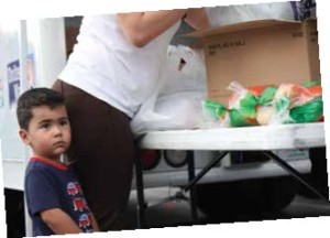 Christian stands in line with his mother at a mobile pantry in March. Forty percent of clients who receive food through the Harry Chapin Food Bank are children.
